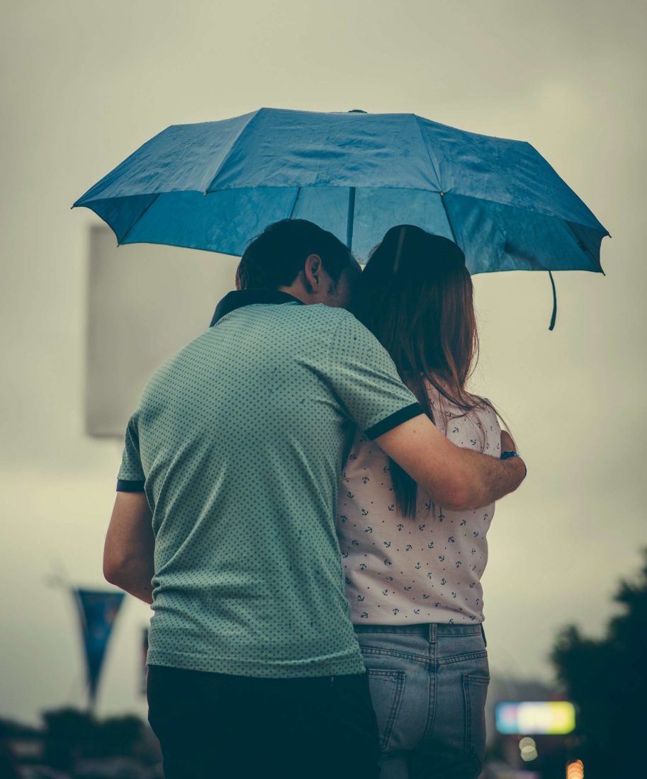 Couple hugging under a blue umbrella