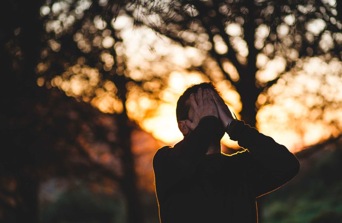 A man with his face in his hands outside