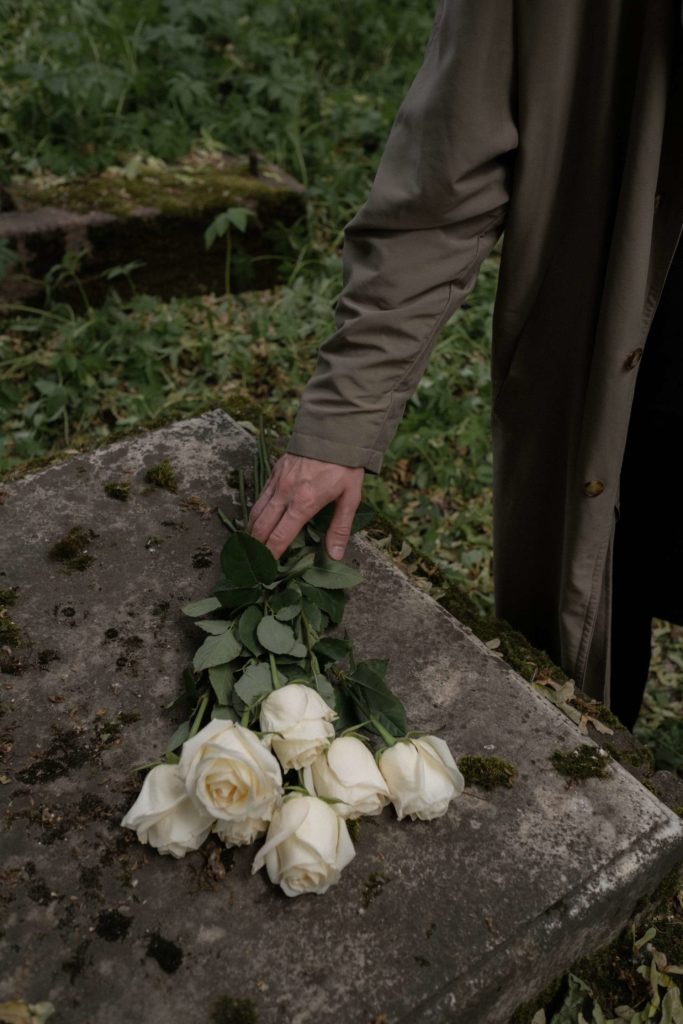 A man laying white roses on a grave
