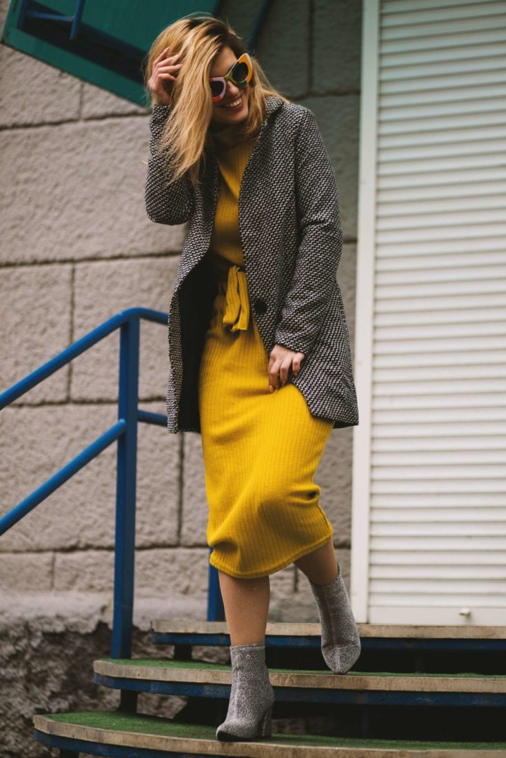 A young woman in a yellow dress and groovy glasses walkign down some steps