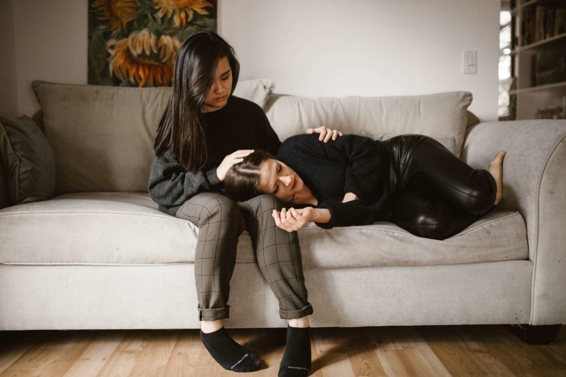 An Asian woman comforting her white friend on a couch