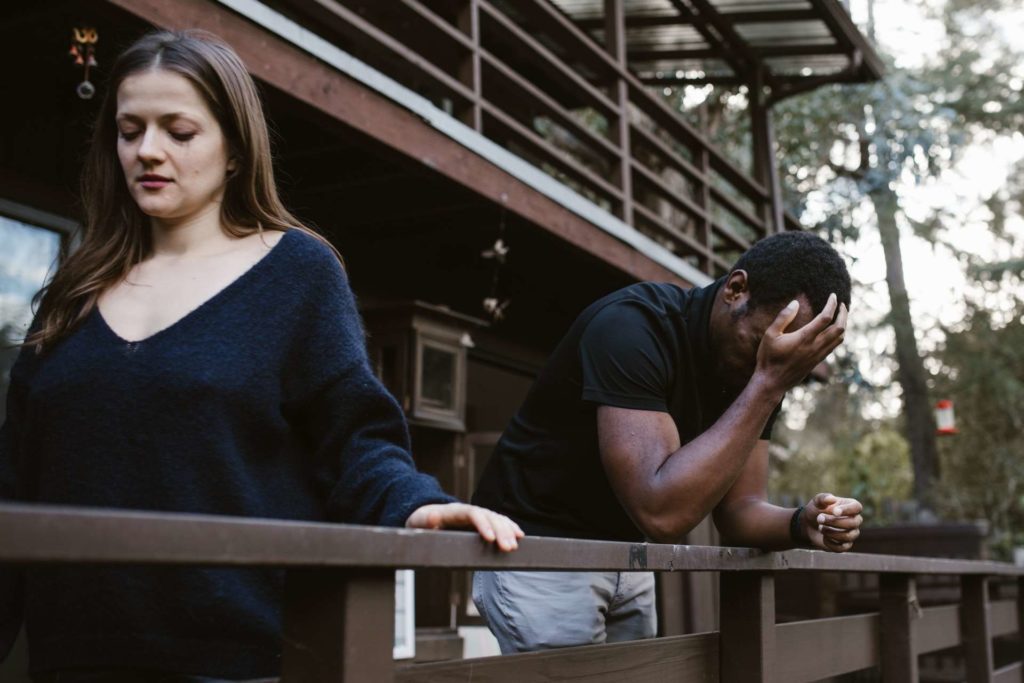A white woman facing away from an upset black man outside