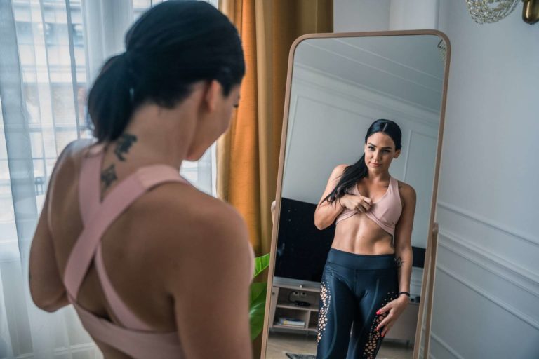 A fit young woman looking at herself in the mirror