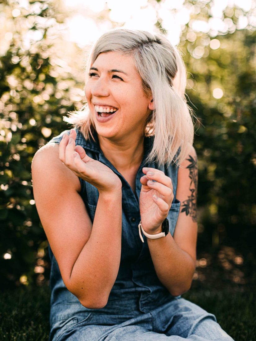 A young blonde woman laughing in a garden