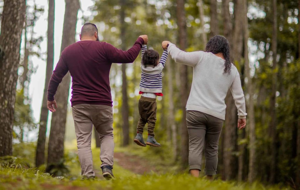 A couple walking in the woods while each holding one of their child's hands
