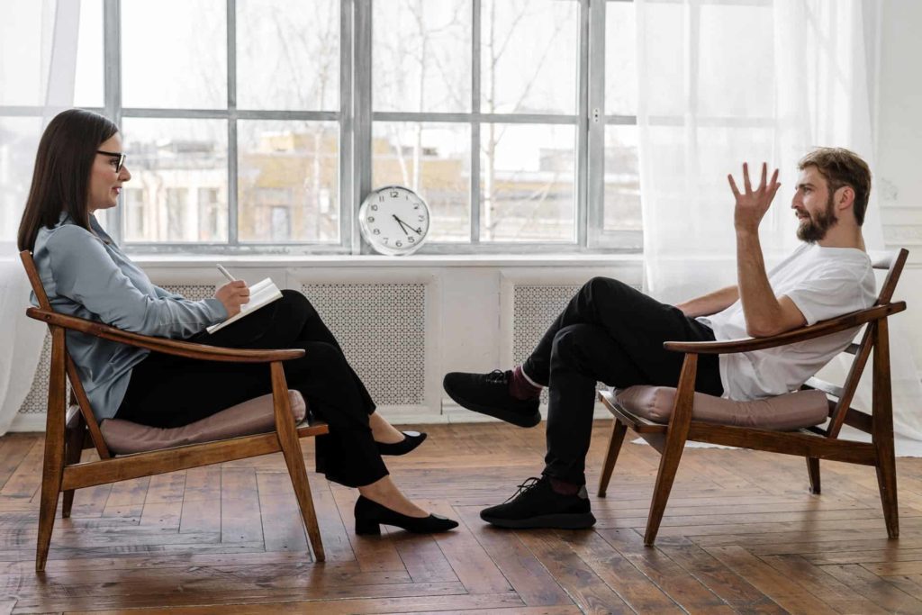 A woman therapist with her male client sitting