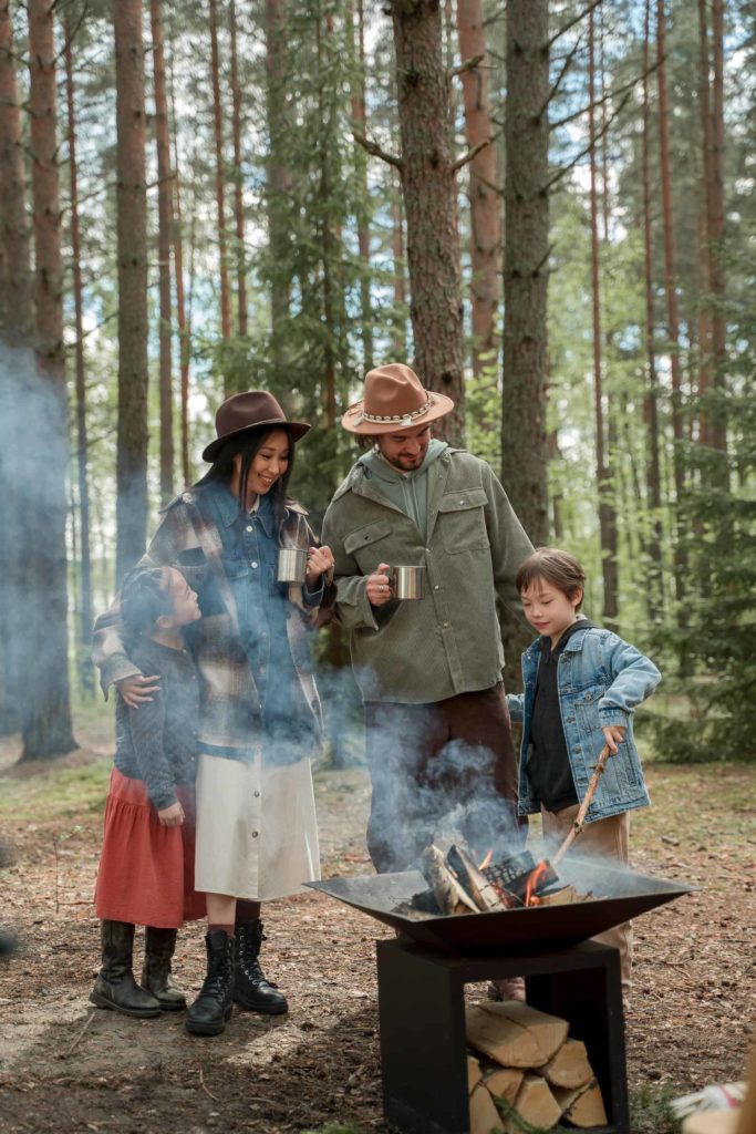 An Asian family standing by a fire in the woods
