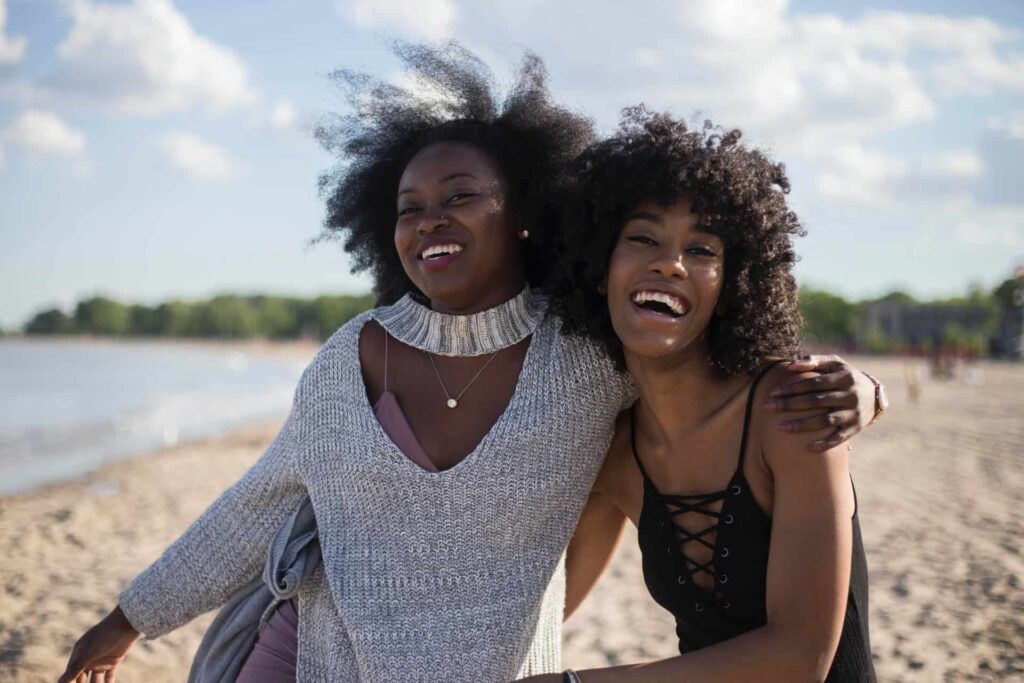 Two black women laughing at the beach