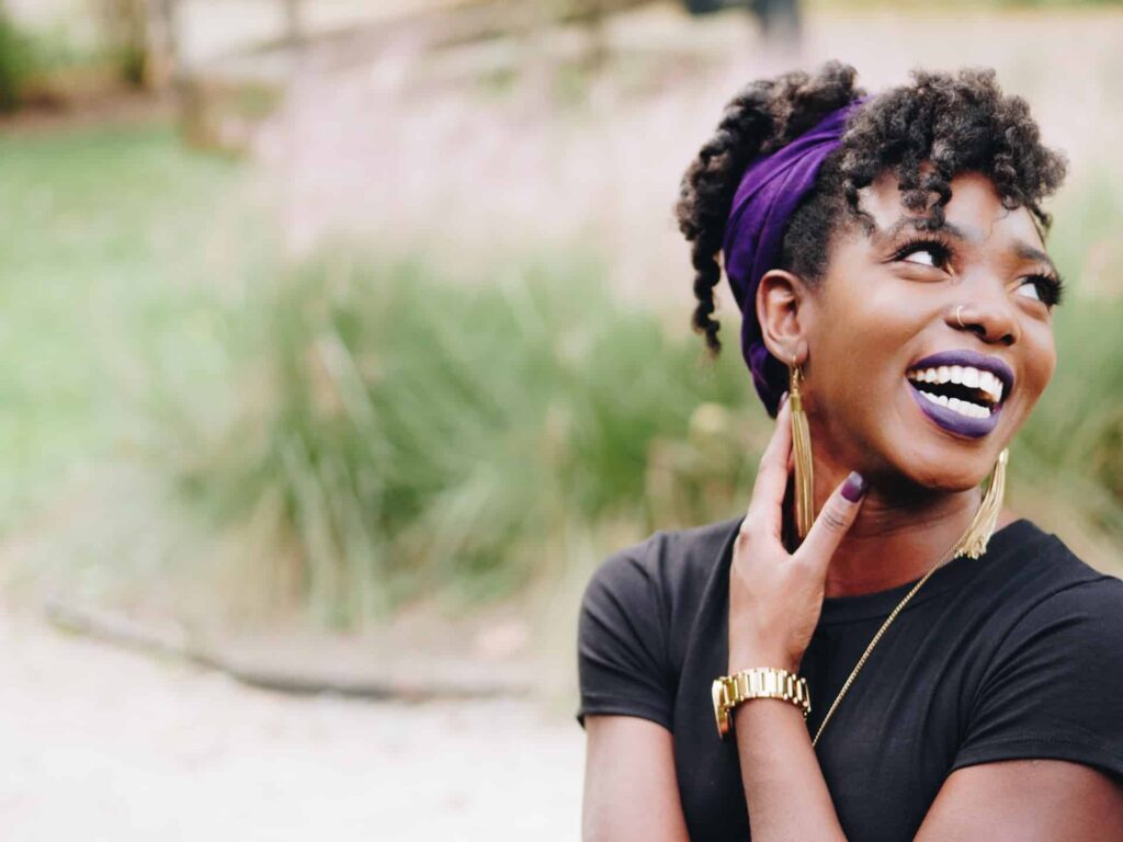 Black woman with a nose piercing laughing outside