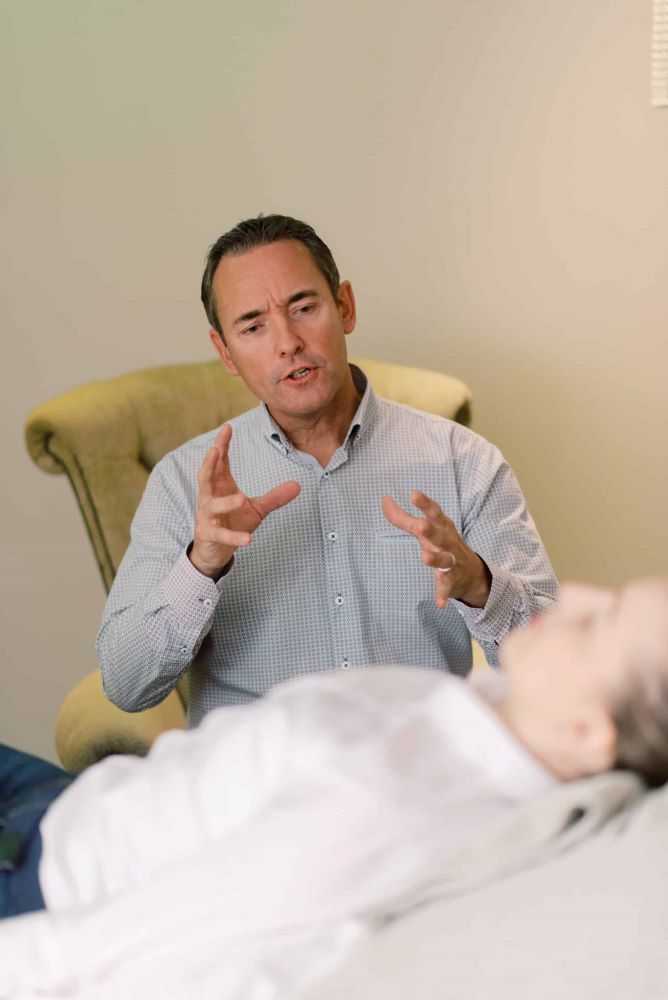 Mental health counselor talks to his patient on a couch in his office