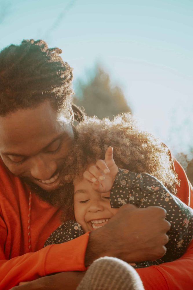 Black father holding and laughing with his young daughter
