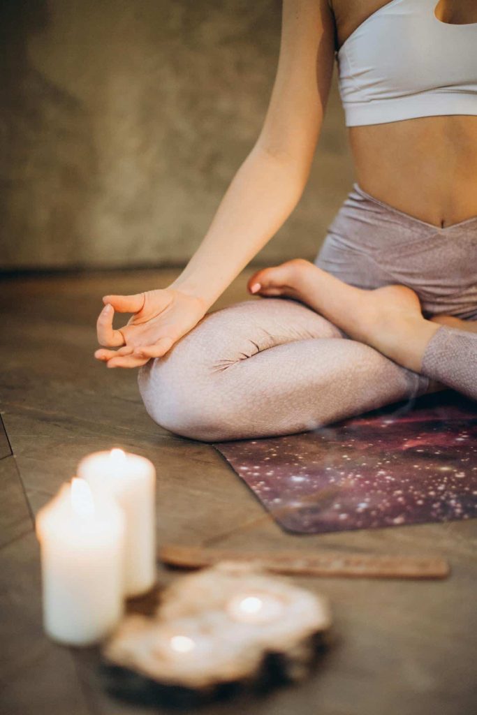 A woman practicing yoga next to candles