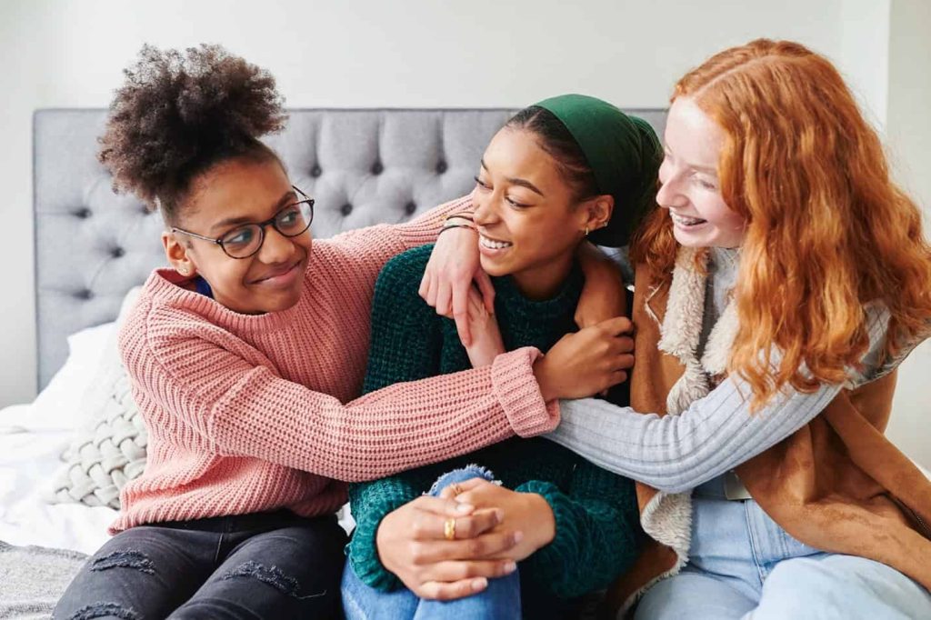 Three girl friends hanging out and hugging